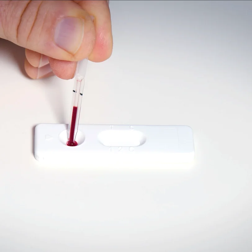 Blut aus der Fingerkuppe wird in die Probenvertiefung gegeben
