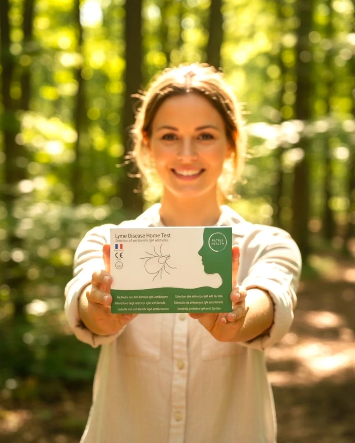Patris Health Borreliose-Selbsttest – Frau im Wald mit der Testbox in der Hand